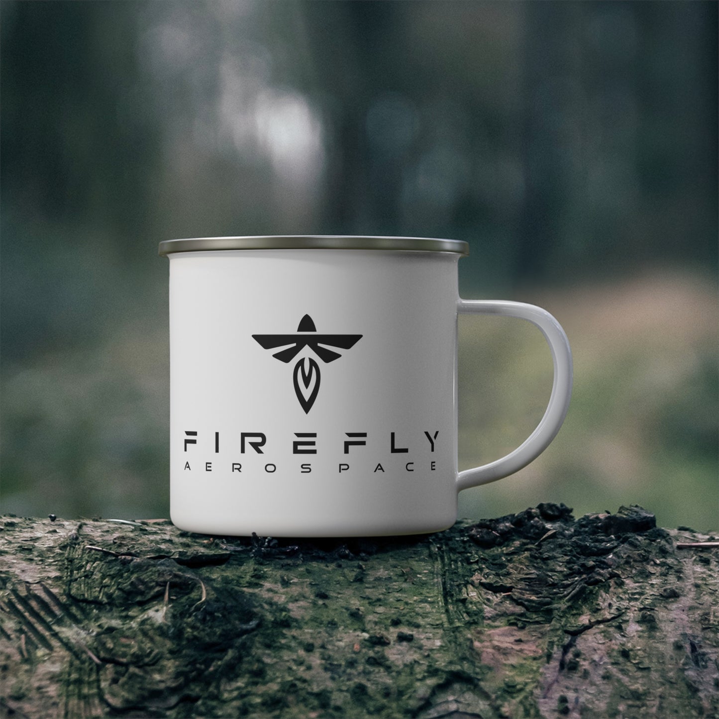A white enamel camp mug with a silver rim and handle, featuring the black 'FIREFLY AEROSPACE' logo, resting on a mossy log with a blurred forest background.