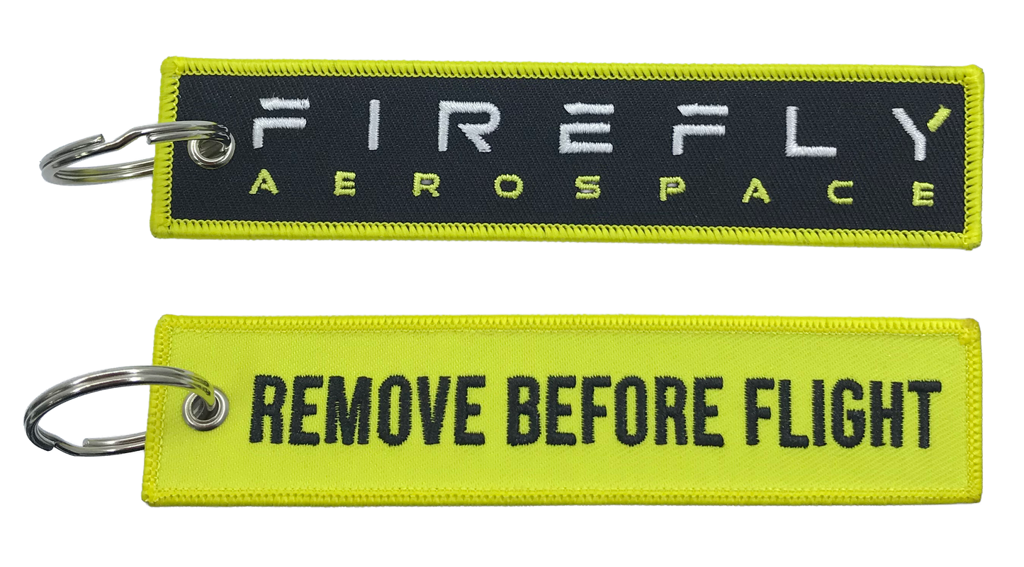 Two keychains with 'Firefly Aerospace' and 'Remove Before Flight' text on a white background.