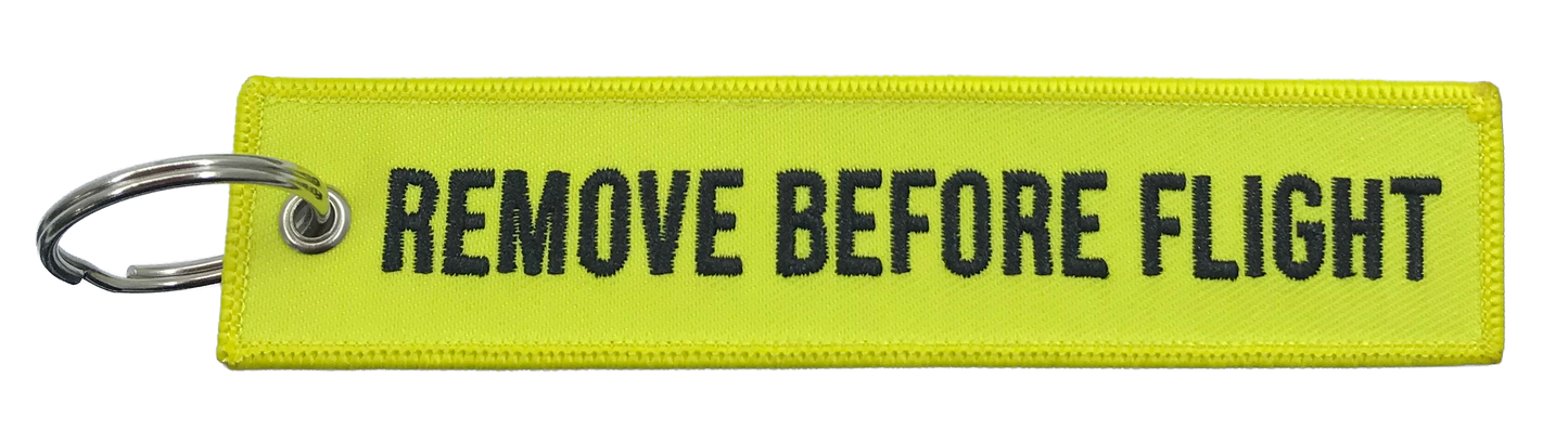 Yellow keychain with 'REMOVE BEFORE FLIGHT' text on a white background