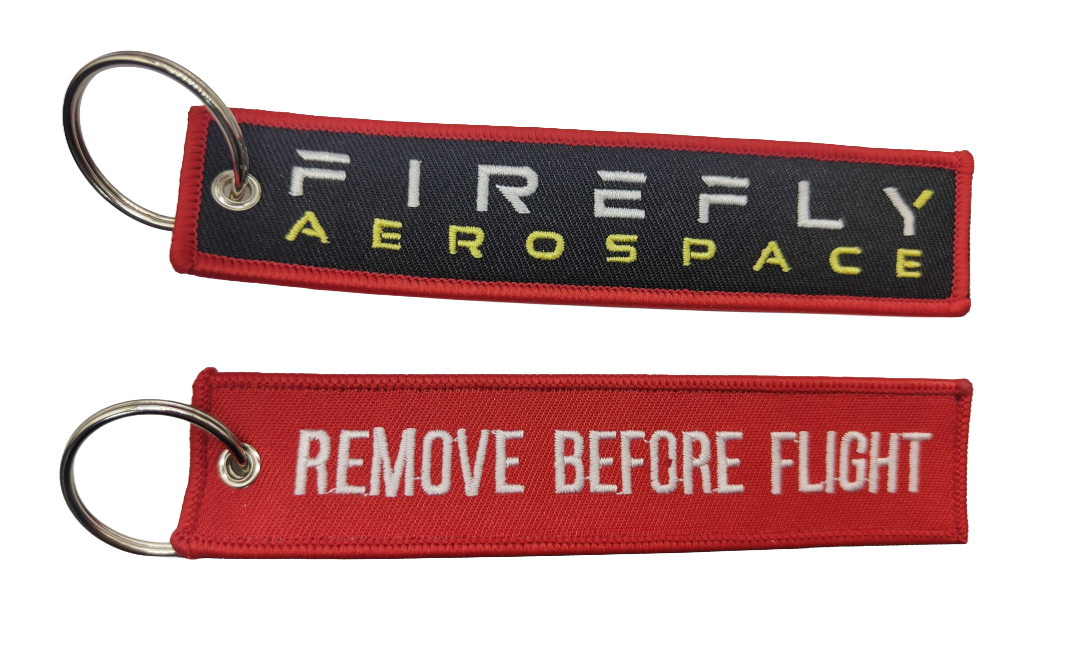 Two keychains with 'Firefly Aerospace' and 'Remove Before Flight' text on a white background.